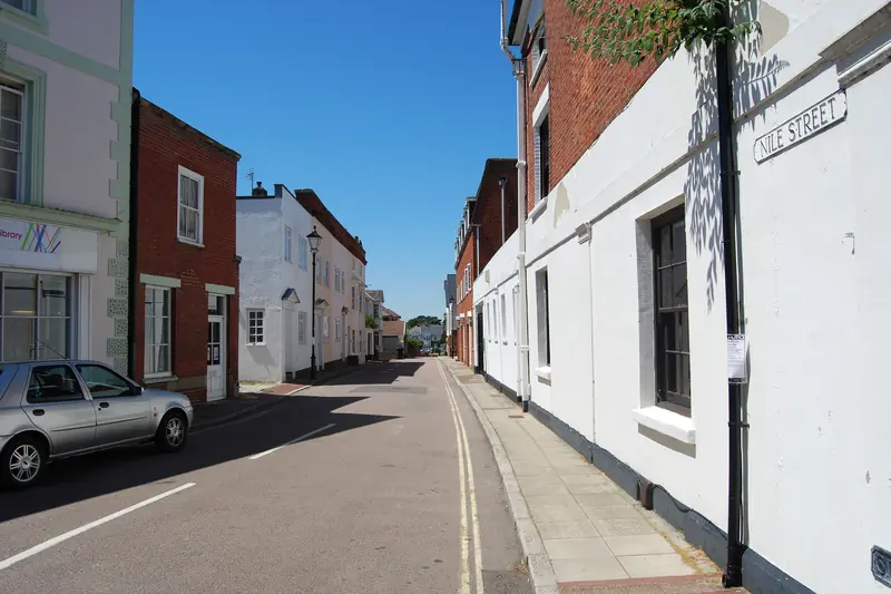 Painted cottages of brick and render lining a narrow lane in Emsworth on a clear day