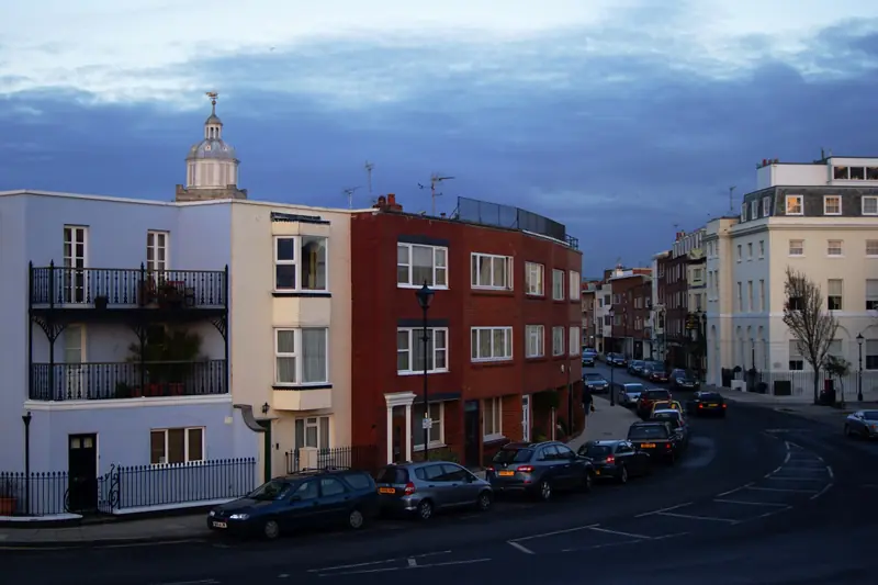 Georgian and Regency townhouses in pale paint along Old Portsmouth's High Street, with wrought-iron balconies and a cupola rising behind